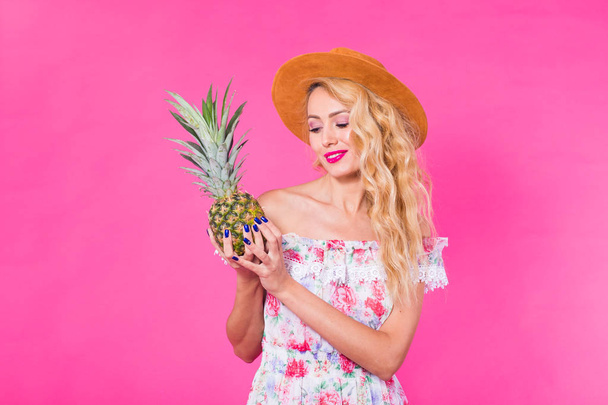 Fashion portrait woman with pineapple over pink background - Fotó, kép