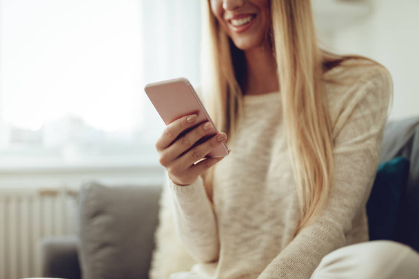 młoda kobieta uśmiechający się przy domu smartphone - Zdjęcie, obraz