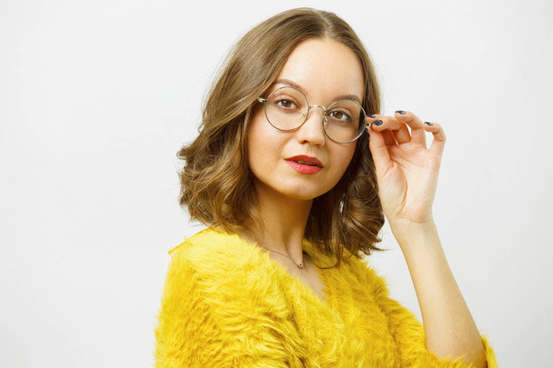 Girl corrects round spectacles and looks at camera over white isolated. - Фото, зображення