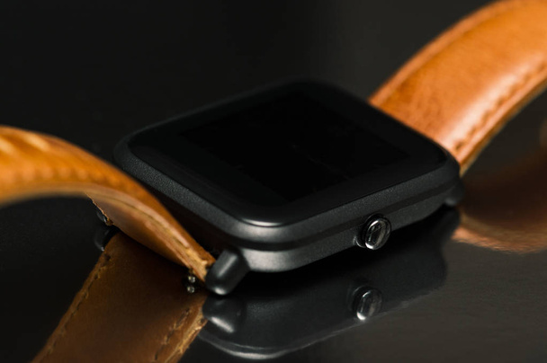 Розумний годинник з коричневим шкіряним ремінцем на відбиваючому фоні
 - Фото, зображення