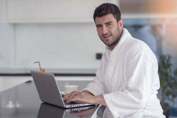 A man in a robe with a laptop at home - Foto, Imagen