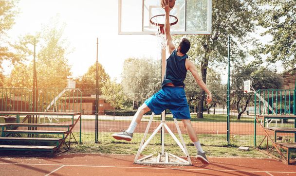 Junger Mann trainiert Basketball auf Straßenplatz - Foto, Bild