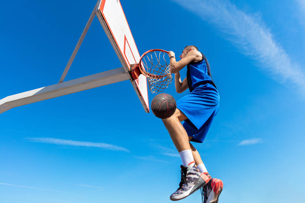 Slam Dunk. Side view of young basketball player making slam dunk - Zdjęcie, obraz