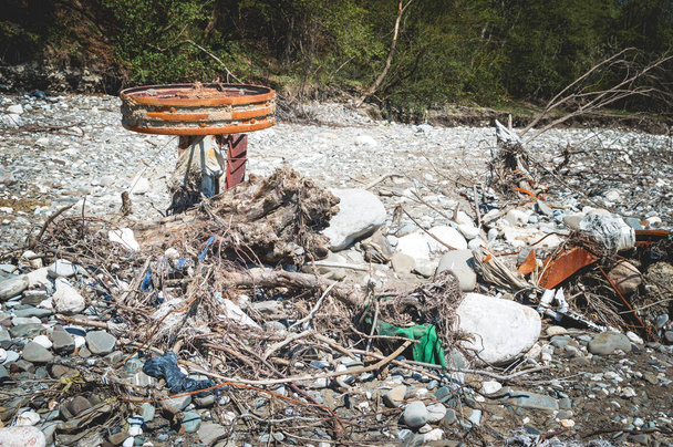 Gegenstände und Äste, die nach der Flut in den Fluss geworfen wurden. Trockenes Flussbett - Foto, Bild