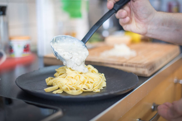 male cooking Pasta with cheese sauce on dark plate - Foto, afbeelding
