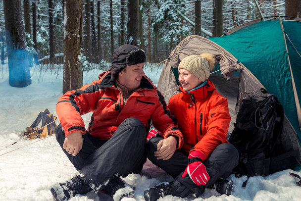 happy couple of active tourists outdoors in the winter forest on - Фото, изображение