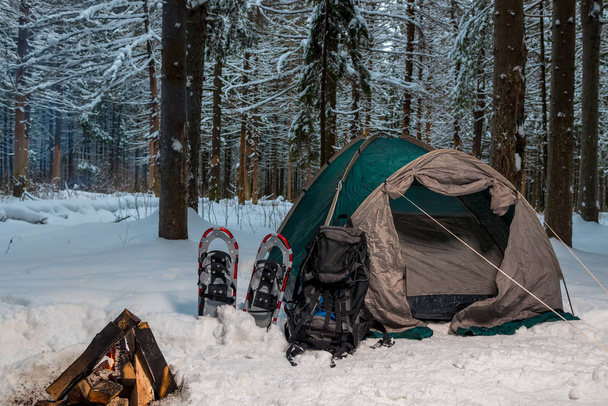 Zelt auf dem Schnee im Winterwald und Lagerfeuer - Foto, Bild