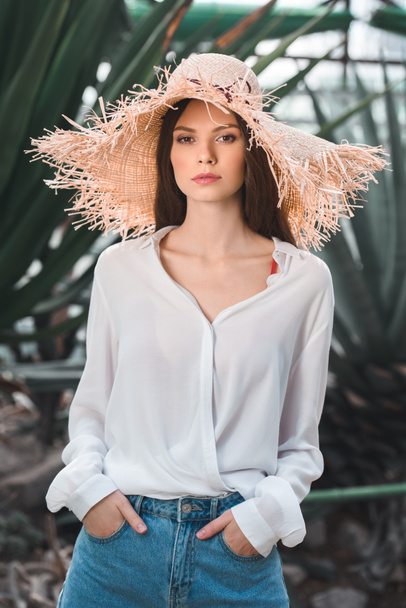 attractive young woman in summer outfit and straw hat posing in tropical garden - Фото, зображення