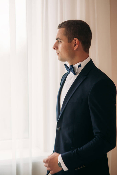 Handsome groom on a wedding day stand near the window - Foto, Imagem