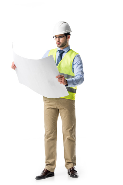 Thoughtful builder in reflective vest and helmet looking at blueprint isolated on white - Foto, Imagem