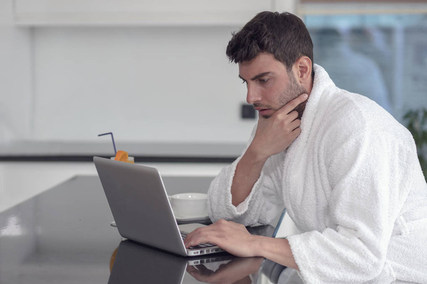 A man in a robe with a laptop at home - Fotografie, Obrázek