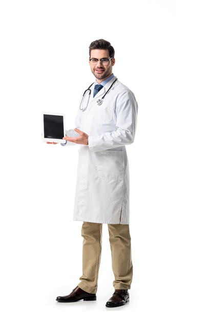 Arzt in Brille mit weißem Mantel und Stethoskop präsentiert digitales Tablet isoliert auf weißem Grund - Foto, Bild