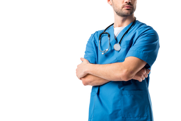 Visão de perto do homem enfermeira vestindo uniforme azul com estetoscópio em pé com os braços dobrados isolados em branco
 - Foto, Imagem