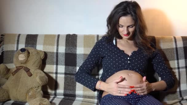 Onnellinen raskaana oleva nainen lepää sohvalla ja silitti vatsaansa
. - Materiaali, video