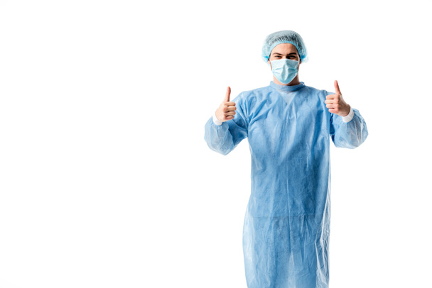 Χειρουργός φορώντας μπλε στολή και ιατρική καπάκι δείχνει μπράβο απομονωθεί σε λευκό - Φωτογραφία, εικόνα