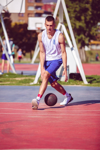 Handsome male playing basketball outdoor - Valokuva, kuva