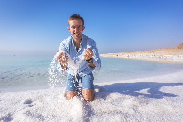 Ttourist ρίχνει αλάτι στην όχθη της Νεκράς θάλασσας. Ιορδανία  - Φωτογραφία, εικόνα