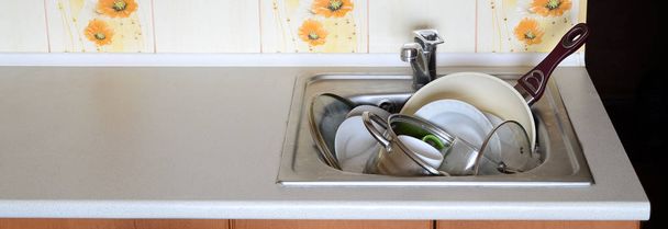 Schmutziges Geschirr und ungewaschene Küchengeräte füllten die Spüle - Foto, Bild