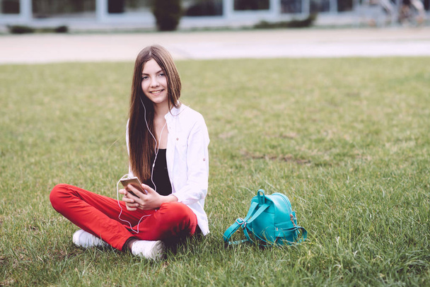 A teenage girl with a smartphone in her hands spends time outdoors. Wonderful spring time - Foto, imagen