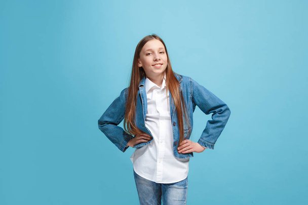 The happy teen girl standing and smiling against blue background. - Фото, зображення