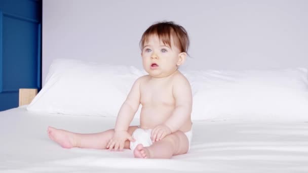 Χαριτωμένο μωρό κάθεται στο κρεβάτι  - Πλάνα, βίντεο
