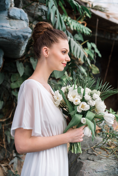 fashionable bride posing in white dress with wedding bouquet - Fotografie, Obrázek