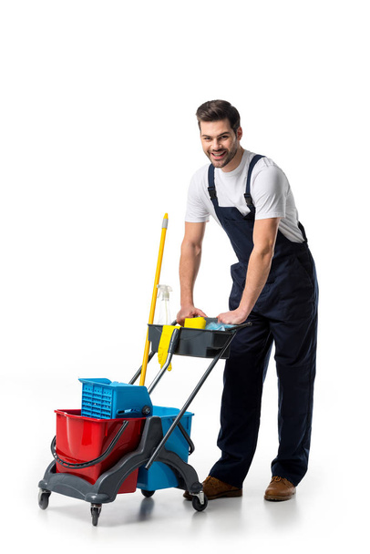 limpiador sonriente en uniforme con carro aislado en blanco
 - Foto, Imagen