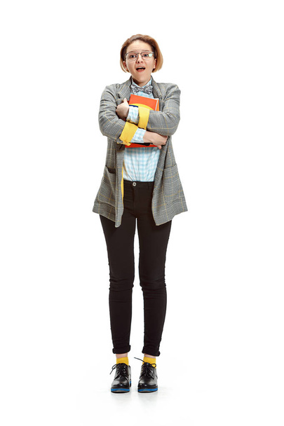 Full length portrait of a surprised female student holding books isolated on white background - Photo, image