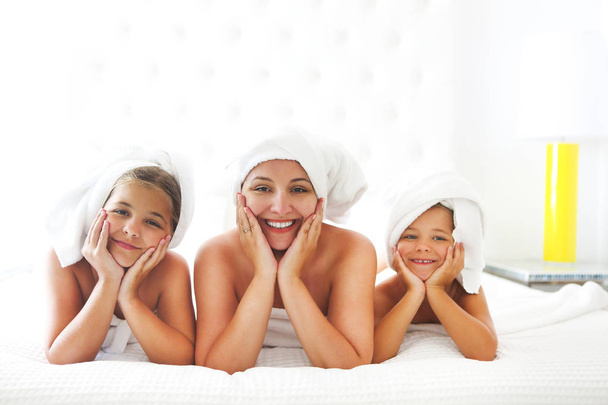 Mãe e meninas em roupões de banho no quarto após o chuveiro
 - Foto, Imagem