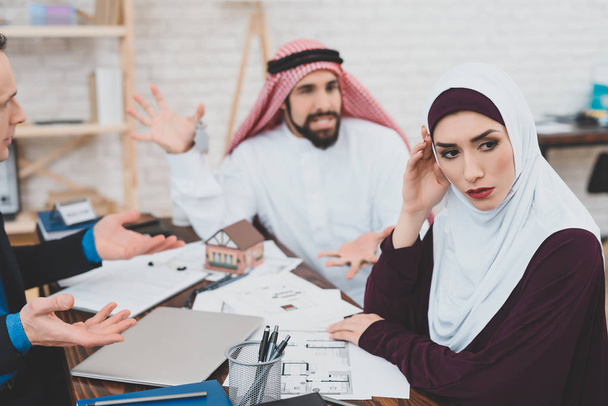 Pareja musulmana discutiendo mientras está sentada en la oficina de la agencia inmobiliaria
 - Foto, Imagen