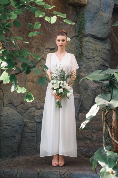 魅力的な花嫁の結婚式の花束と白いドレスでポーズ - 写真・画像