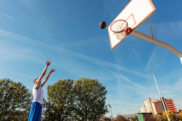 Young man shooting free throws from the foul line - 写真・画像
