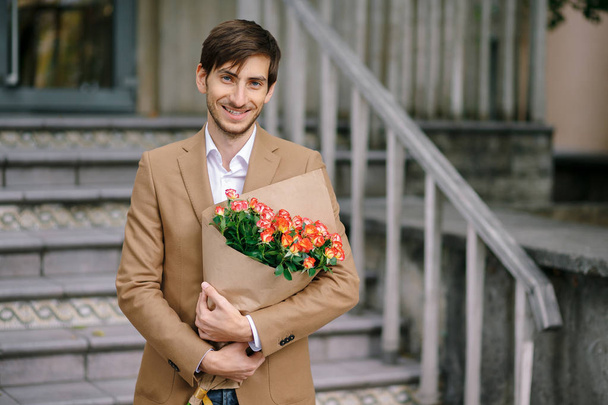 Hombre guapo sosteniendo ramo de rosas sonrisas mostrando dientes
 - Foto, Imagen