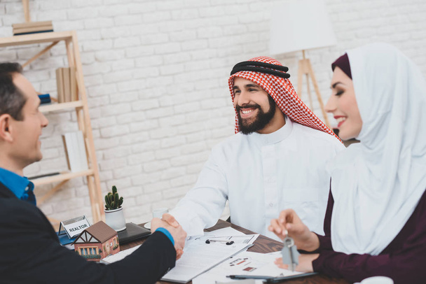 Realtor shaking hands with Arab man sitting in office - Photo, Image