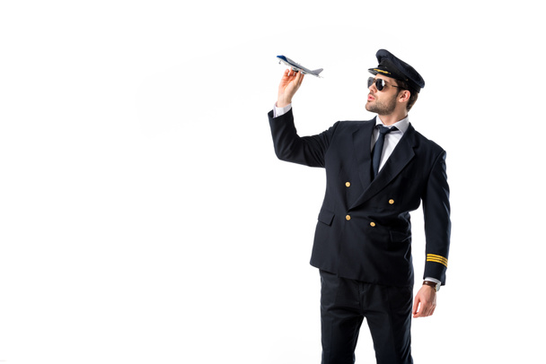 young bearded pilot in uniform and sunglasses with toy plane isolated on white - Valokuva, kuva
