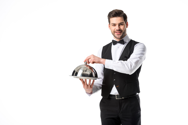 retrato de camarero guapo sonriente en chaleco de traje con bandeja aislada en blanco
 - Foto, imagen