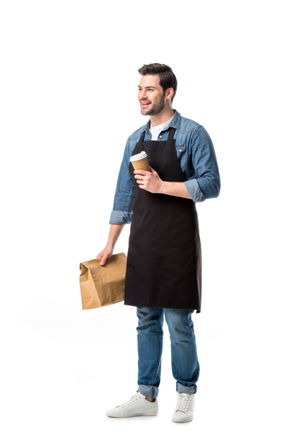 smiling waiter in apron with order to go in hands isolated on white - Foto, afbeelding