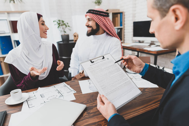Realtor reading terms of purchase and sale agreement for young Muslim couple  - 写真・画像