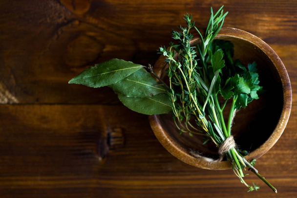 bowl with bouquet garni and bay leaves with fresh herbs on dark wooden background - Фото, зображення