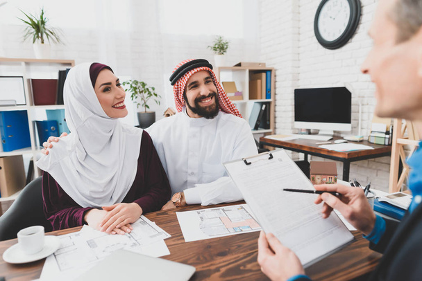 Realtor reading terms of purchase and sale agreement for young Muslim couple  - Zdjęcie, obraz