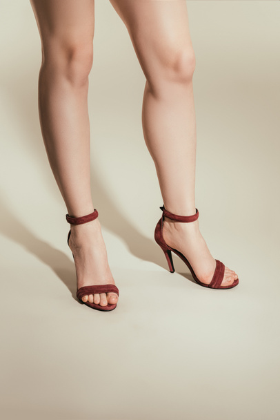 cropped image of woman legs in high heeled sandals on white background - Fotó, kép