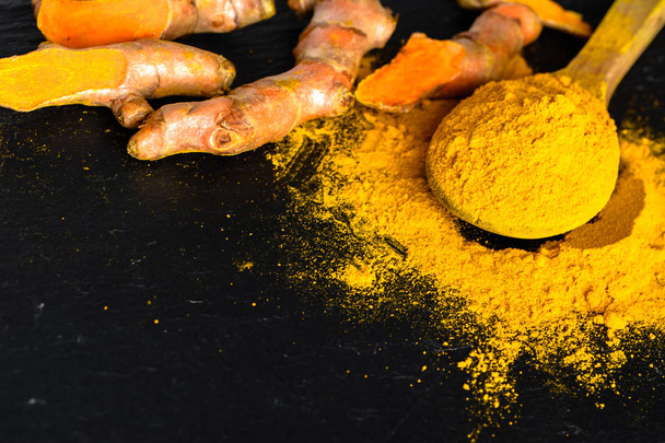 Raíz fresca y cúrcuma en polvo, especias indias, ingrediente de condimento saludable para la cocina vegana
 - Foto, imagen