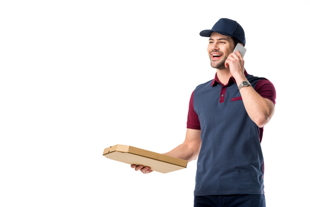 πορτρέτο της χαμογελαστός άνθρωπος παράδοσης με κουτί χάρτινο πίτσας μιλάμε για smartphone που απομονώνονται σε λευκό - Φωτογραφία, εικόνα