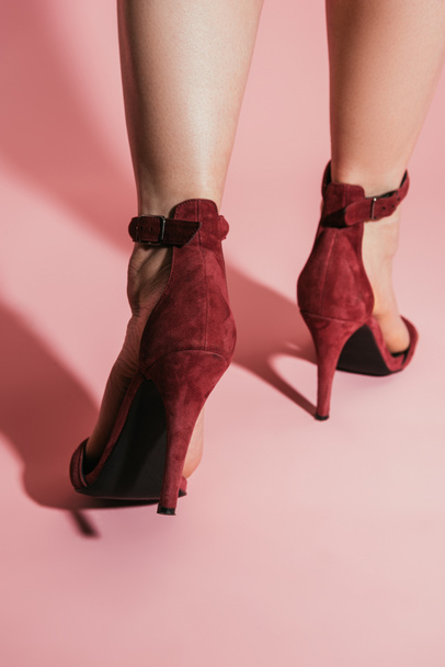 cropped image of woman feet in stylish high heeled sandals on pink background - Valokuva, kuva