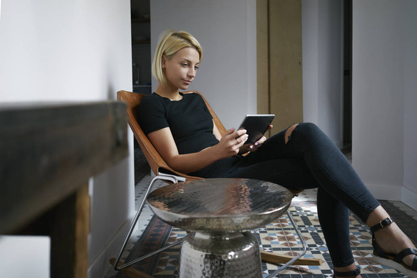 young female writes in a blog on her digital tablet in a vintage interior - Foto, Bild