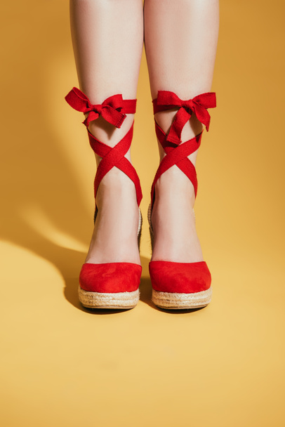 image recadrée de pieds de femme dans des sandales de plate-forme élégantes sur fond jaune
 - Photo, image