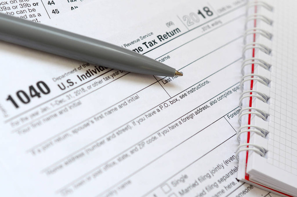 La pluma y el cuaderno son mentiras en el formulario de impuestos 1040 EE.UU. Declaración individual del impuesto sobre la renta. El momento de pagar impuestos
 - Foto, imagen