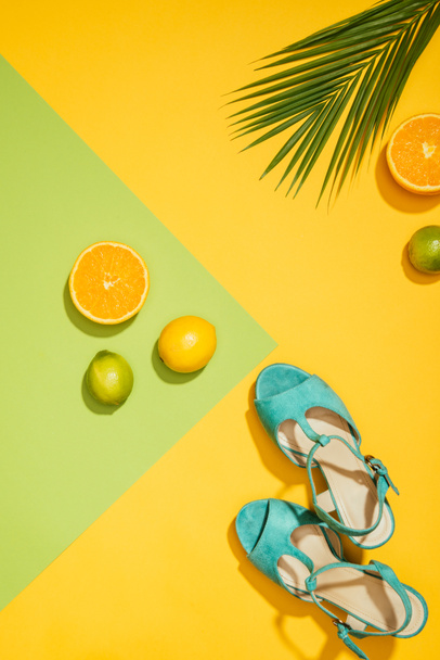 top view of palm leaf, stylish female blue platform sandals, lemons, limes and slices of orange - Foto, imagen