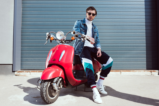 handsome young man in denim jacket on vintage red scooter - Фото, зображення