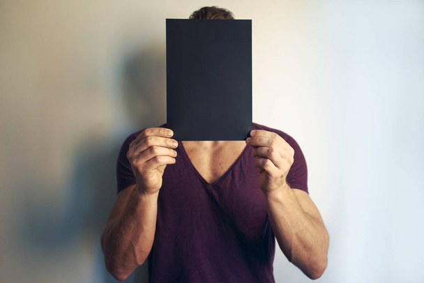 Young man holding blank black envelope in front of his face - 写真・画像